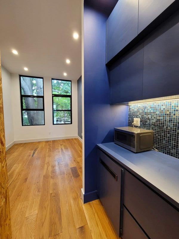 bar featuring baseboards, stainless steel microwave, backsplash, and light wood-style floors