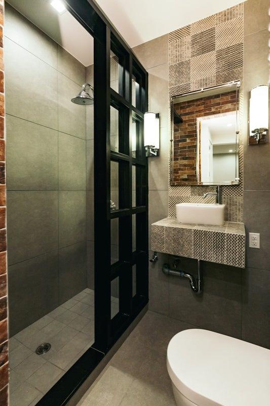 bathroom featuring toilet, a sink, tile walls, and a shower stall