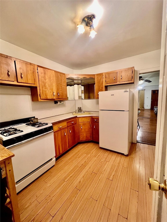 kitchen featuring sink, light hardwood / wood-style floors, and white appliances