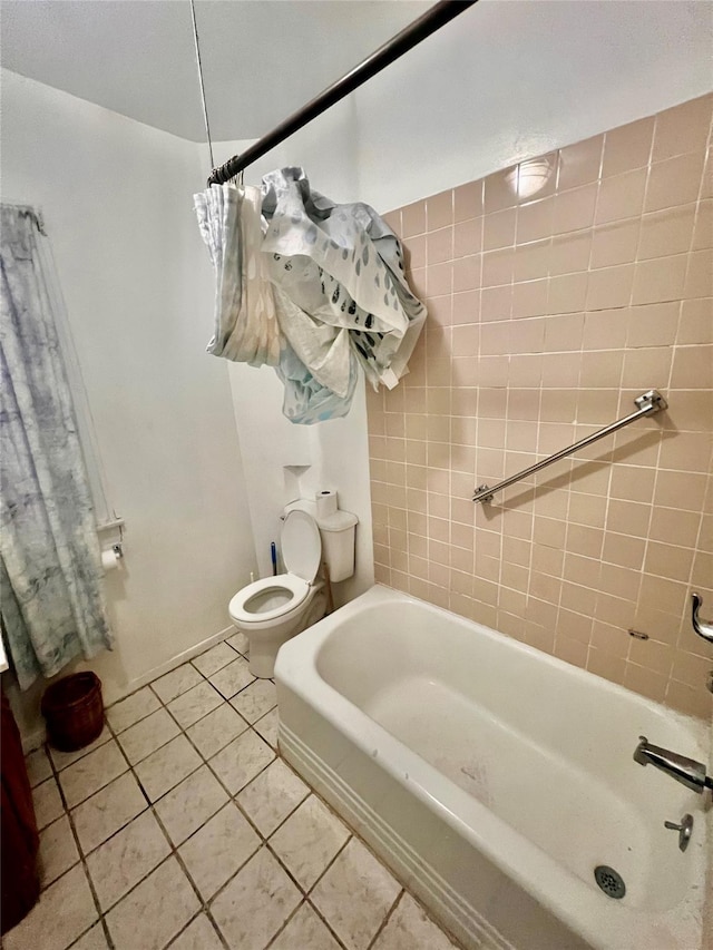 bathroom with tile patterned flooring, tiled shower / bath combo, and toilet