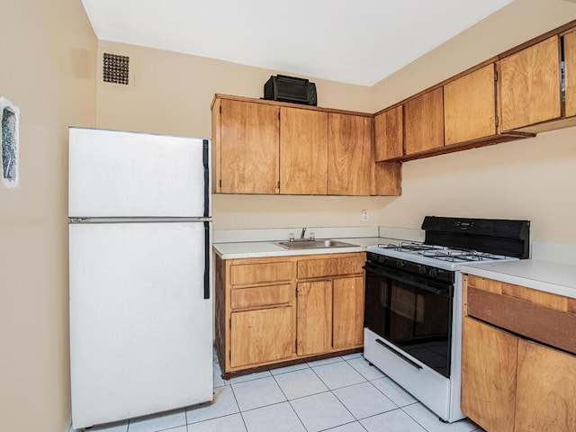 kitchen featuring white appliances, sink, and light tile patterned floors