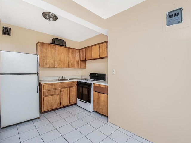 kitchen with white appliances, sink, and light tile patterned floors