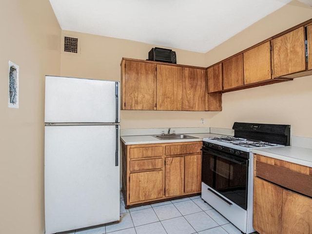 kitchen featuring white appliances, sink, and light tile patterned floors