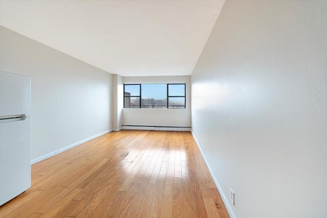 unfurnished room with baseboard heating and light hardwood / wood-style flooring