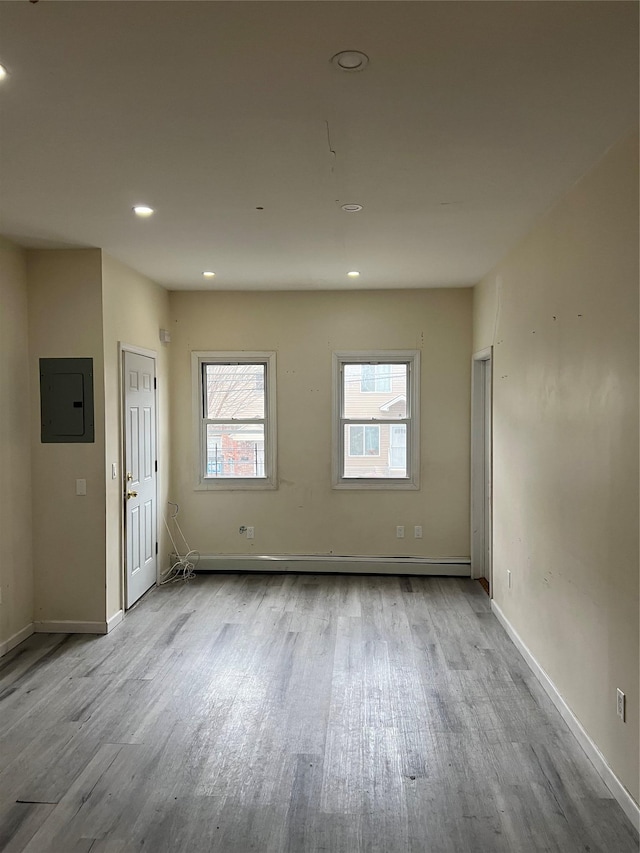 unfurnished room featuring electric panel and light hardwood / wood-style flooring