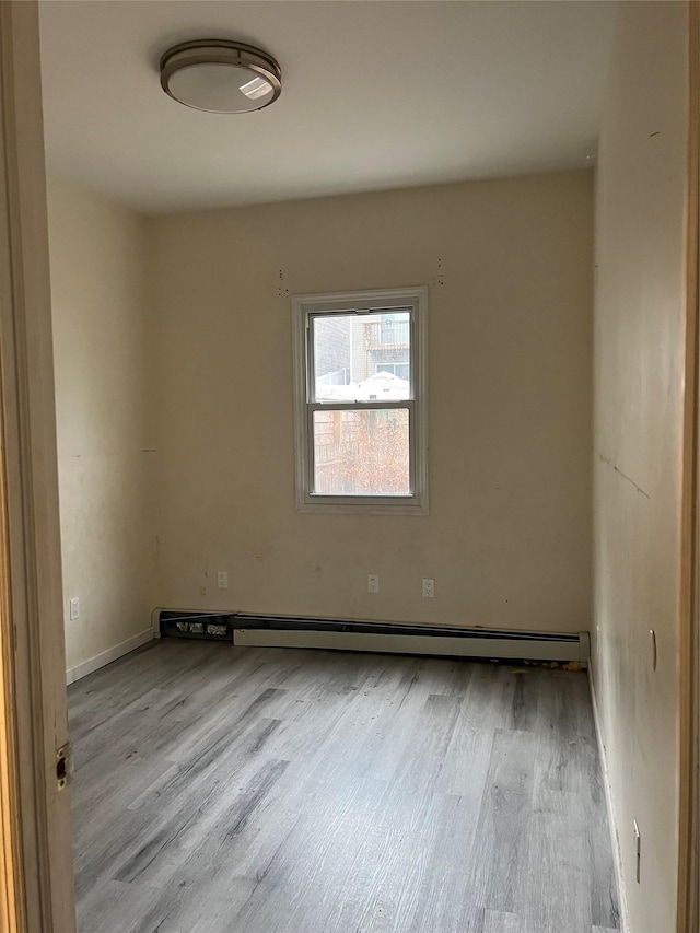 unfurnished room featuring baseboard heating and light hardwood / wood-style flooring