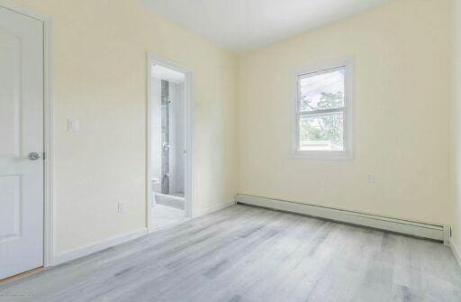 88 Taft Ave, Staten Island, NY 10301 - spare room featuring baseboard heating and wood finished floors
