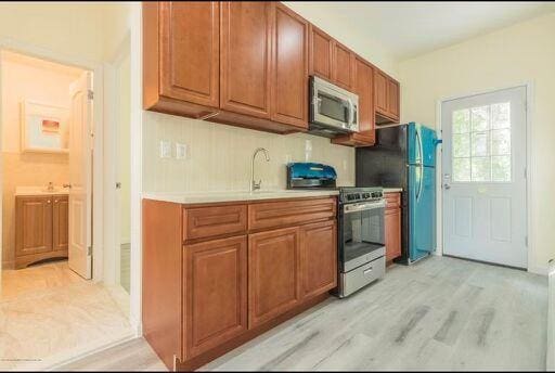 88 Taft Ave, Staten Island, NY 10301 - kitchen featuring stainless steel appliances, light countertops, brown cabinetry, and light wood-style flooring