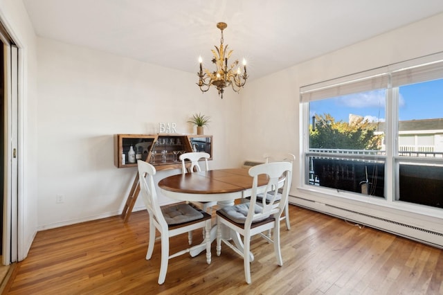 dining space with hardwood / wood-style floors, a chandelier, and a baseboard heating unit