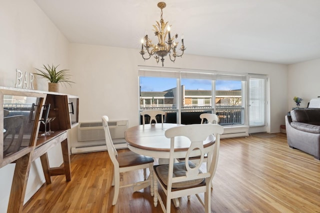 dining room with a wall unit AC, a baseboard radiator, a notable chandelier, and light wood-type flooring