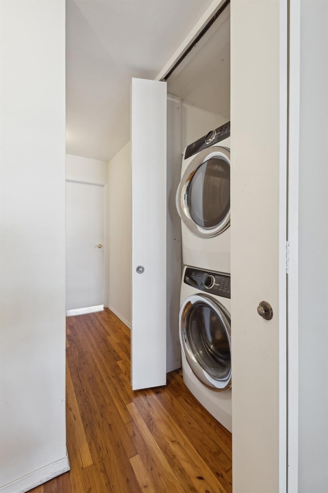 laundry room featuring wood-type flooring and stacked washer / drying machine