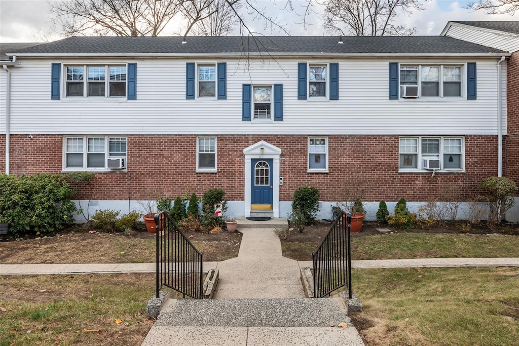 view of front of house with a front yard and cooling unit