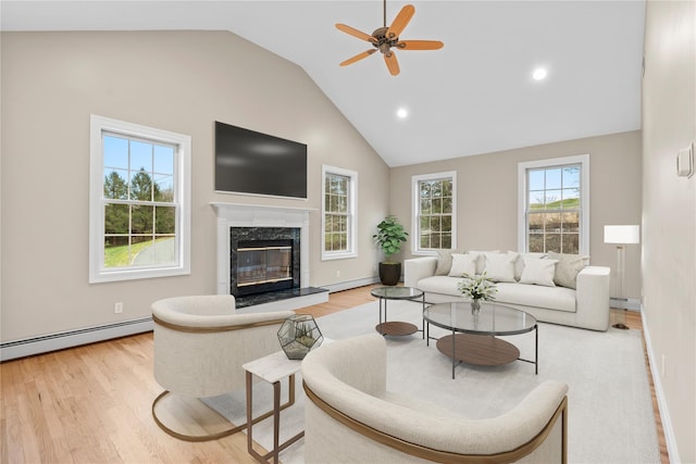 living room featuring a premium fireplace, light wood-type flooring, baseboard heating, and vaulted ceiling