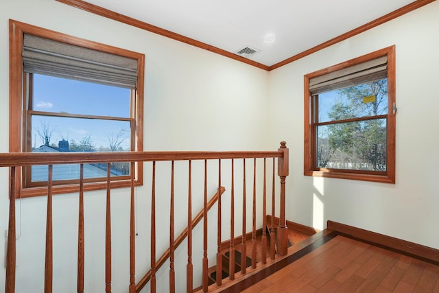 stairs featuring a healthy amount of sunlight, wood-type flooring, and crown molding