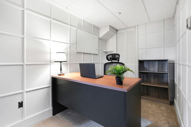 carpeted office with a paneled ceiling