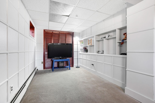 unfurnished living room with a paneled ceiling, carpet flooring, built in features, and baseboard heating