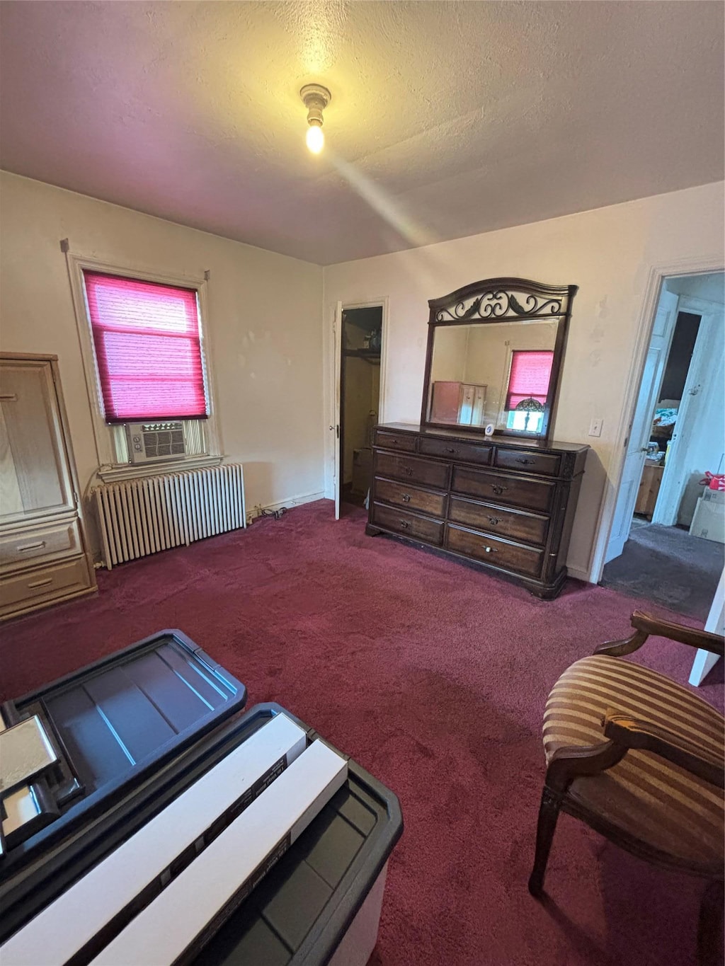 carpeted bedroom featuring a textured ceiling and radiator heating unit