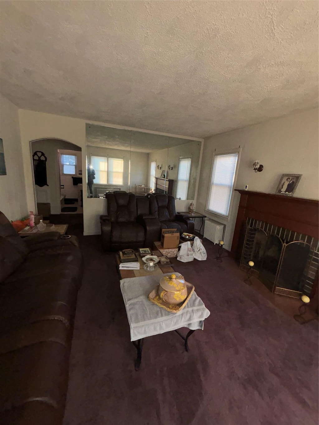 living room featuring a textured ceiling, a fireplace, plenty of natural light, and radiator heating unit