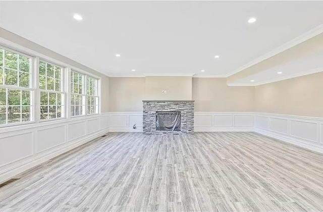 unfurnished living room with a fireplace, light hardwood / wood-style floors, and ornamental molding