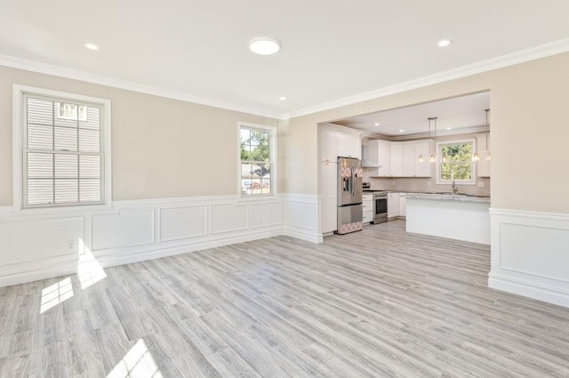 unfurnished living room featuring light hardwood / wood-style floors, crown molding, and sink