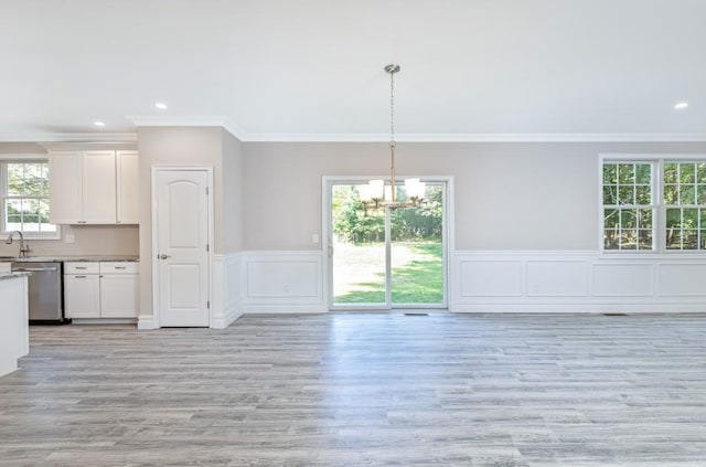 unfurnished dining area featuring a healthy amount of sunlight, sink, crown molding, and light hardwood / wood-style flooring