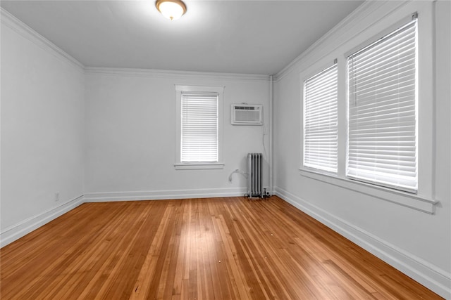 spare room featuring a wall mounted air conditioner, light hardwood / wood-style floors, crown molding, and radiator