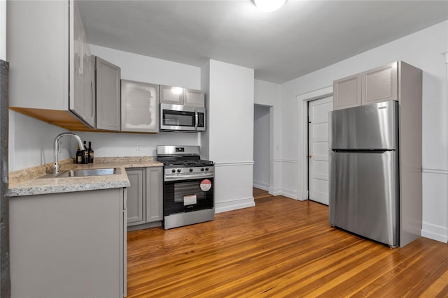 kitchen featuring gray cabinets, sink, appliances with stainless steel finishes, and light hardwood / wood-style flooring