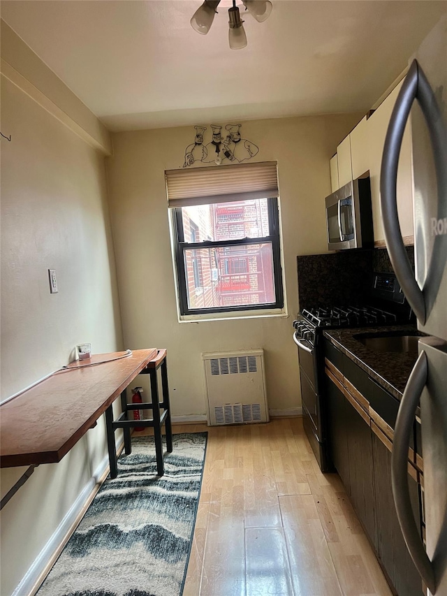 kitchen with white cabinetry, black range with gas stovetop, light wood-type flooring, and radiator