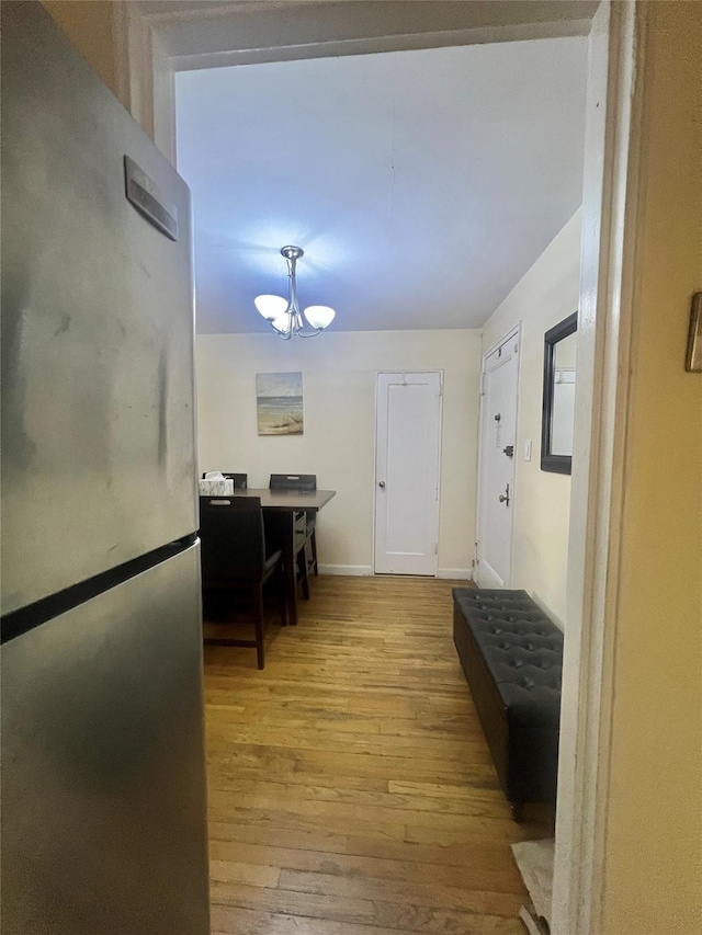 hall featuring light hardwood / wood-style flooring and a notable chandelier