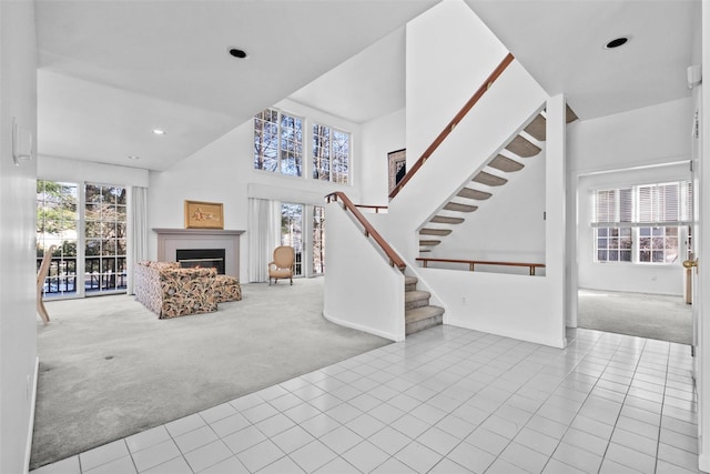 unfurnished living room with light carpet, a towering ceiling, and plenty of natural light