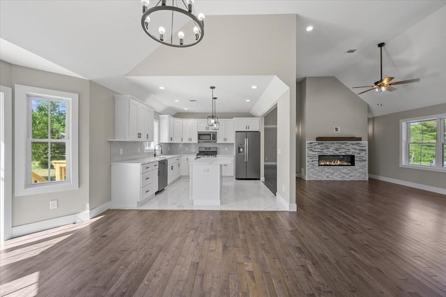 kitchen featuring a center island, pendant lighting, a fireplace, white cabinets, and appliances with stainless steel finishes