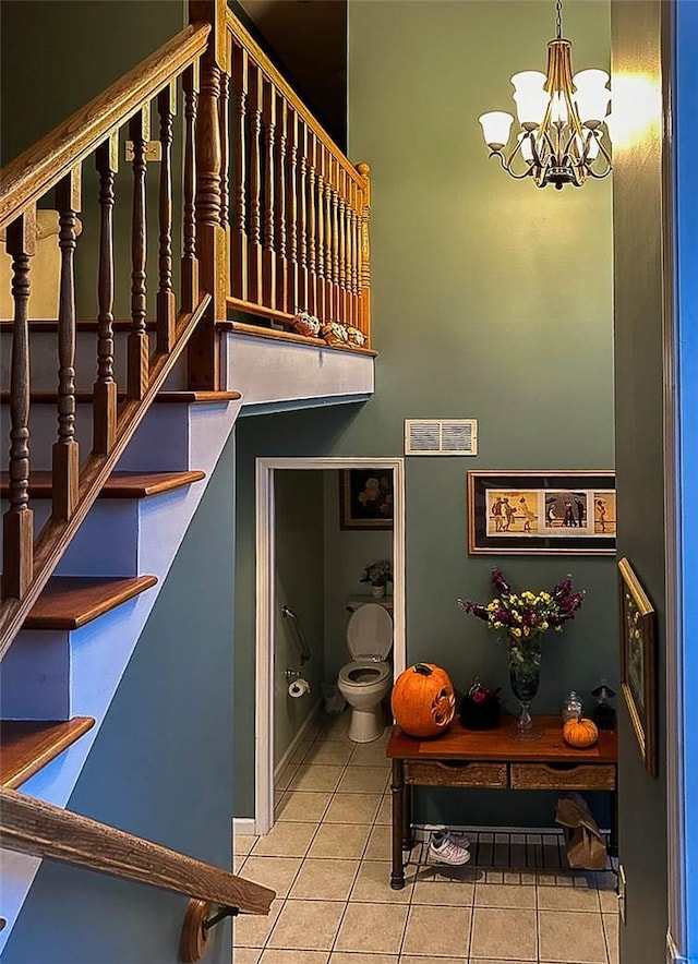 stairs with tile patterned flooring and a notable chandelier