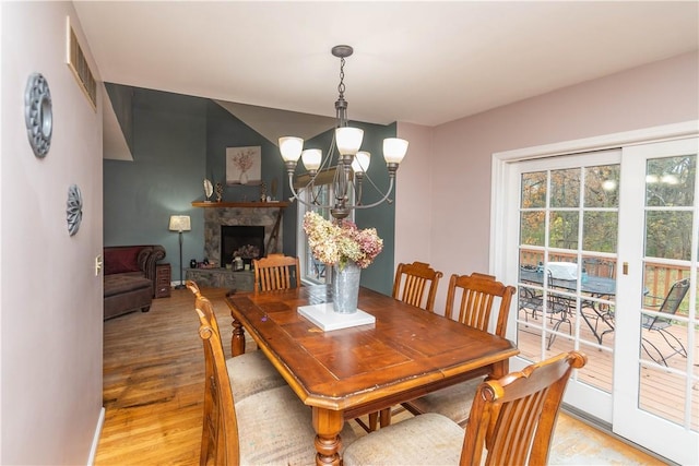 dining area with light hardwood / wood-style floors, a fireplace, and a chandelier