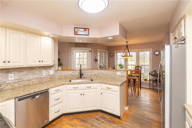 kitchen with kitchen peninsula, appliances with stainless steel finishes, dark hardwood / wood-style flooring, and plenty of natural light