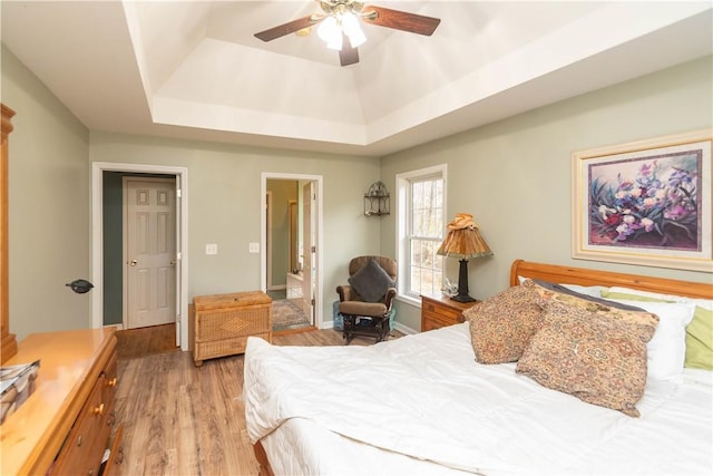 bedroom featuring hardwood / wood-style flooring, ceiling fan, and a tray ceiling