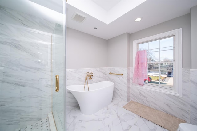 bathroom with shower with separate bathtub and tile walls