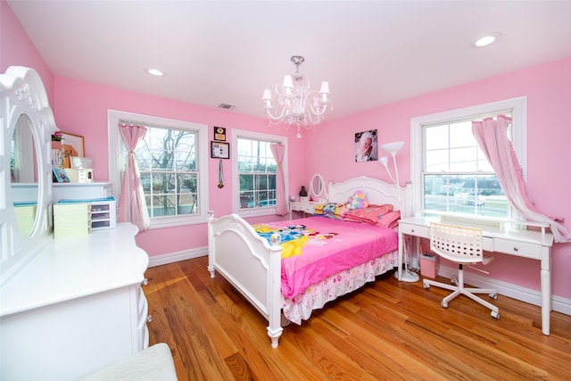 bedroom featuring hardwood / wood-style floors, a notable chandelier, and multiple windows