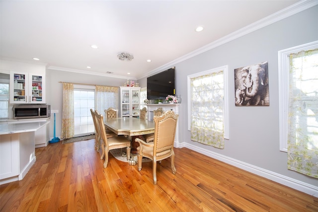 dining room with a wealth of natural light, crown molding, and light wood-type flooring