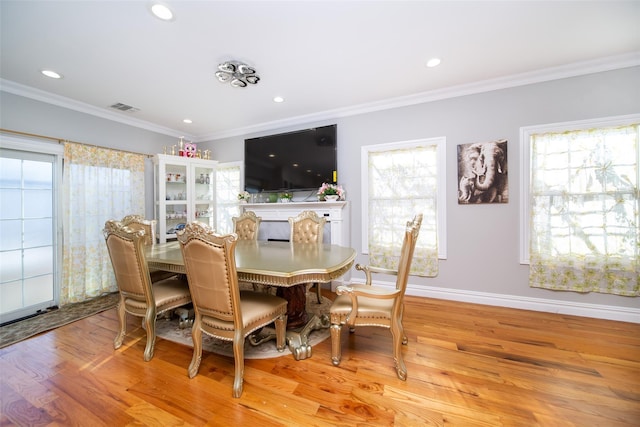 dining space featuring ornamental molding and light hardwood / wood-style flooring