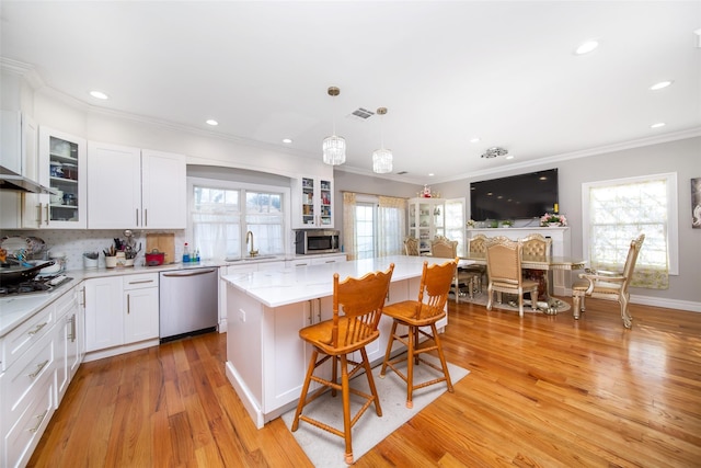 kitchen featuring white cabinets, a kitchen island, stainless steel appliances, and light hardwood / wood-style floors