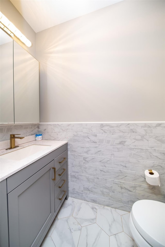 bathroom featuring vanity, toilet, and tile walls