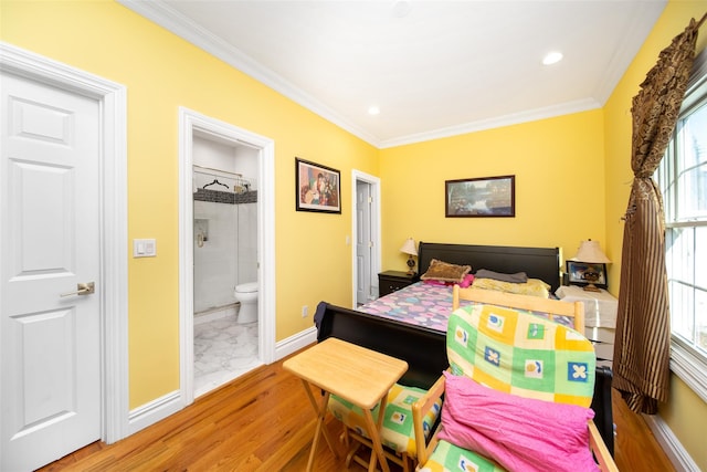 bedroom with connected bathroom, hardwood / wood-style flooring, and ornamental molding