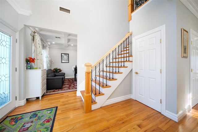 foyer entrance with hardwood / wood-style floors, crown molding, coffered ceiling, and beam ceiling