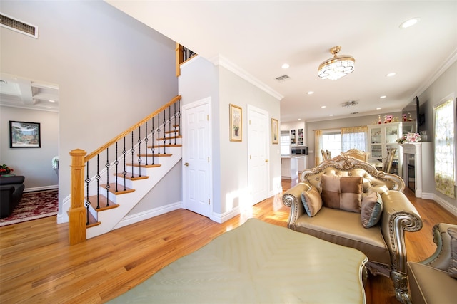 living room with crown molding, a healthy amount of sunlight, and light wood-type flooring