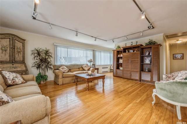 living room with track lighting, ornamental molding, radiator heating unit, and light hardwood / wood-style flooring