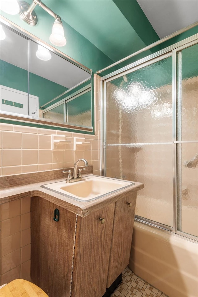 bathroom with backsplash, vanity, shower / bath combination with glass door, tile walls, and tile patterned flooring