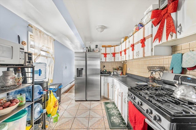 kitchen with light tile patterned floors, white cabinetry, backsplash, and appliances with stainless steel finishes