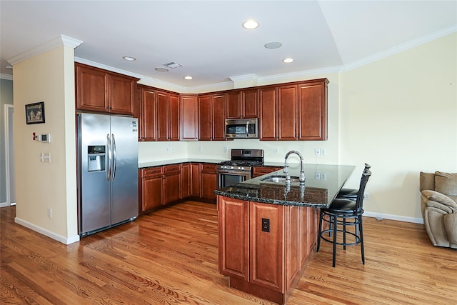 kitchen featuring sink, stainless steel appliances, kitchen peninsula, wood-type flooring, and a breakfast bar area