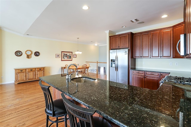 kitchen with a kitchen breakfast bar, hanging light fixtures, light hardwood / wood-style flooring, ornamental molding, and appliances with stainless steel finishes