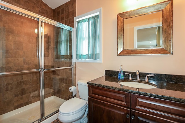 bathroom featuring vanity, a shower with shower door, and toilet